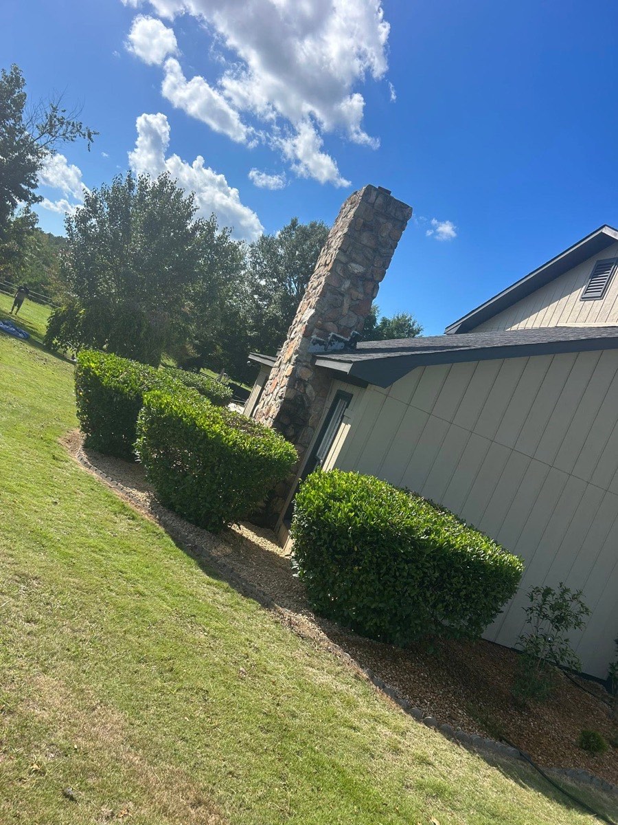 Squared-off hedges along a home with rock beds